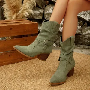 Close-up of green suede slouchy western boots with decorative buckle and chunky heel