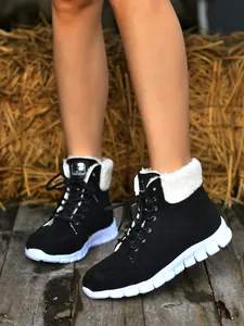 Detail van zwarte veterschoenen met witte voering van imitatiebont en dikke zool