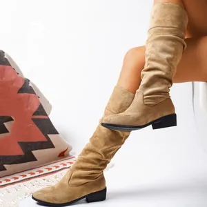 Detail of tan suede slouchy knee-high boots with pointed toe and black mid-block heel