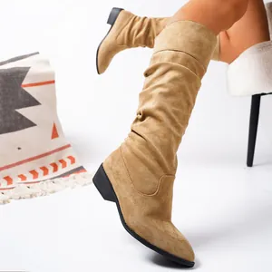 Detailed close-up of tan suede slouchy high knee boots showing wrinkled shaft texture.