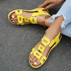 Detailed view of yellow wedge sandals with decorative metal buckles and elastic straps