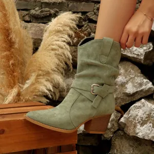 Close-up of sage green suede western boots with buckle strap and chunky mid-heel