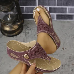 Primer plano de sandalias de cuña moradas con calados láser y hebilla de metal