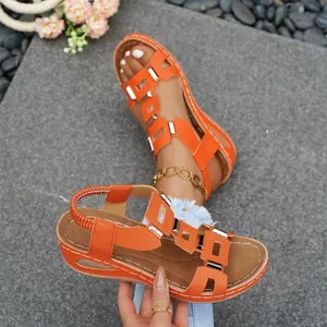 Close-up of vibrant orange wedge sandals with metal buckle and elastic strap