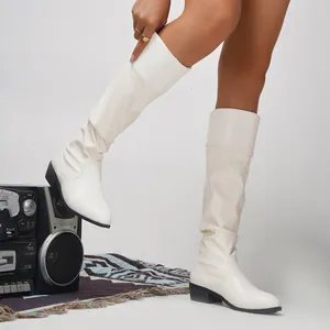 Detail view of stylish white slouchy knee-high boots with pointed toe and mid-heel