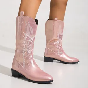 Close-up detail of stylish pink metallic western boots with white wing embroidery