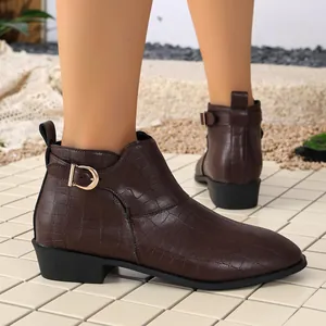 Detailed view of brown crocodile pattern ankle boots with gold buckle and low block heel