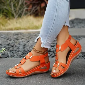 Close-up of bright orange wedge sandals with peep toe and gold metal buckle details