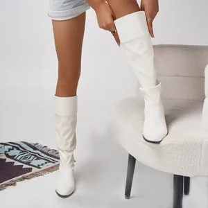 Close-up of white slouchy knee-high boots featuring soft pleats and mid-heel for autumn winter