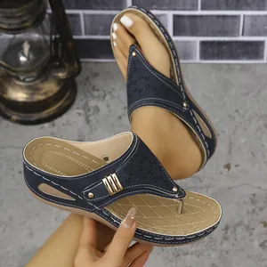 Detalle de sandalias con cuña azul marino con hebilla dorada y diseño calado a láser