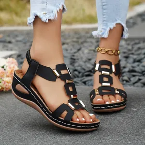 Close-up view of stylish black wedge sandals with metallic buckles and cutout design