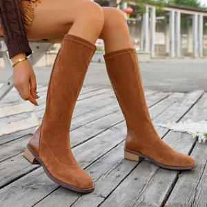 Elegant brown suede knee-high boots with square toe and low block heel shown on a model.