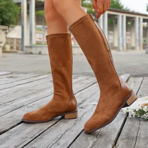 Detailed shot of stylish brown suede knee-high boots featuring a low square heel and zipper
