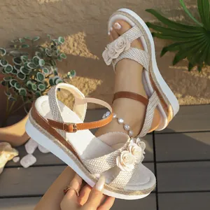 Detail van beige sleehak sandalen met touwzool en stoffen bloemdecoratie
