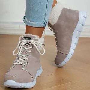 Casual taupe enkellaarsjes met witte voering van imitatiebont en veters op houten vloer