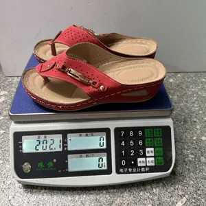 Rode wedge slippers met gouden gesp die 202 gram wegen op een weegschaal