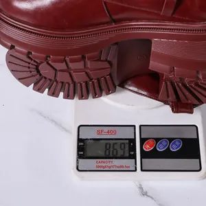 Close-up of burgundy platform tall boot weight measurement at 869g on a digital scale