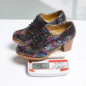 Close-up of colorful textured lace-up block heel pumps weighing 482.0g on a scale