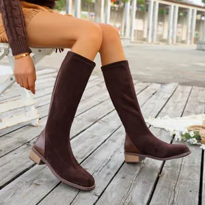 Brown suede knee-high boots with square toe and low heel, styled in an outdoor setting