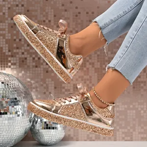 Detail of gold glitter platform sneakers with shiny mirror finish and lace-up design.