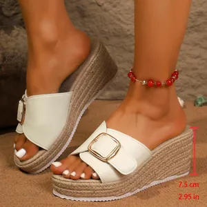 Close-up detail of white platform wedge sandals with woven hemp sole and golden buckle