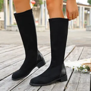 Detailed view of black knee-high boots featuring suede finish and low block heel