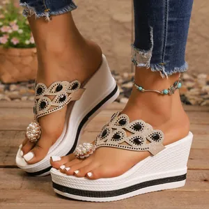 Detalle de sandalias de cuña blancas con adornos de pedrería y perlas
