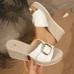 Close-up of white summer wedge sandal with woven jute sole and gold buckle detail