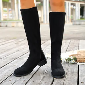 Elegant black square-toe knee-high boots on a model in a scenic outdoor setting.