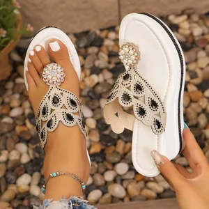 Detalle de sandalias de cuña blancas con pedrería y decoraciones florales de perlas