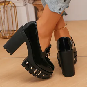Nahaufnahme der schwarzen Plateau-Loafer aus Lackleder mit 11 cm hohem Blockabsatz am Fuß.