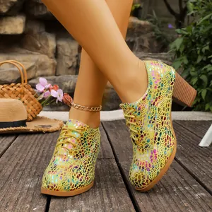Close-up view of yellow multi-color patterned lace-up chunky heel pumps on a wooden deck