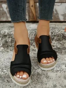 Gros plan de sandales à talons compensés avec semelle en corde de chanvre et tige en cuir noir
