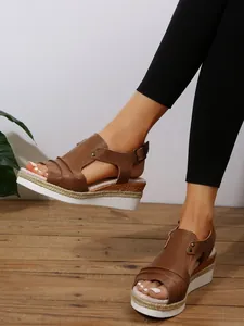 Gros plan de sandales compensées marron avec détail en corde d'espadrille et bout ouvert