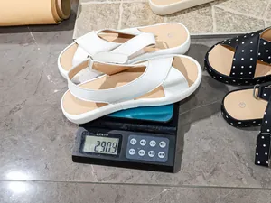 Detailed view of lightweight white flat sandals weighing 290.9 grams on a scale.