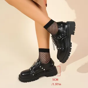 Detail of black platform shoes with metal chains, studs, and a 5cm thick sole.