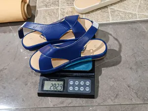 Detailed shot of lightweight blue flat sandals weighing 282.9g on a digital scale.