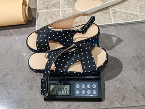 Weight demonstration of black polka dot sandals on a digital scale showing 294.6 grams