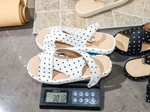 Close-up view of a white polka dot sandal on a digital scale showing its light weight
