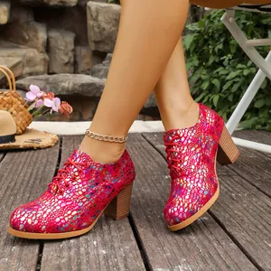 Macro view of the vibrant red pebbled texture and lace-up detail on chunky heels.