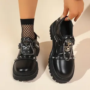 Macro view of gothic black loafers with metallic silver skull and chain details