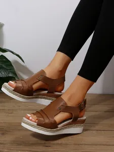 Gros plan de sandales compensées marron avec détail en corde aux pieds du mannequin
