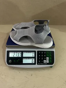 Gedetailleerd overzicht van de gewichtsmeting van een grijze flyknit-sandaal op een weegschaal