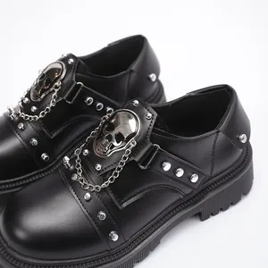 Detail shot of black punk platform shoes with skull charms and chain accents.