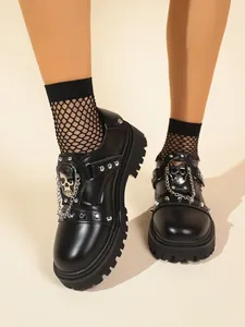 Close-up detail of black platform shoes with silver skull, rivet and gothic chain accents.