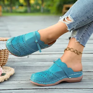 Detailed view of blue laser-cut leather mules for women resting on a wooden deck