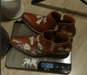 Vintage brown ankle boots with floral embroidery shown on a digital scale for weight detail.