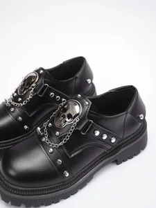 Close-up of goth punk platform shoes with silver skull medallion and metal chain details