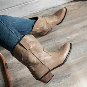 Gros plan de bottes de cowboy occidentales beiges brodées pour femmes à talons hauts