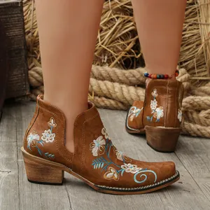 Detail view of brown western ankle boots with blue floral embroidery and square toe